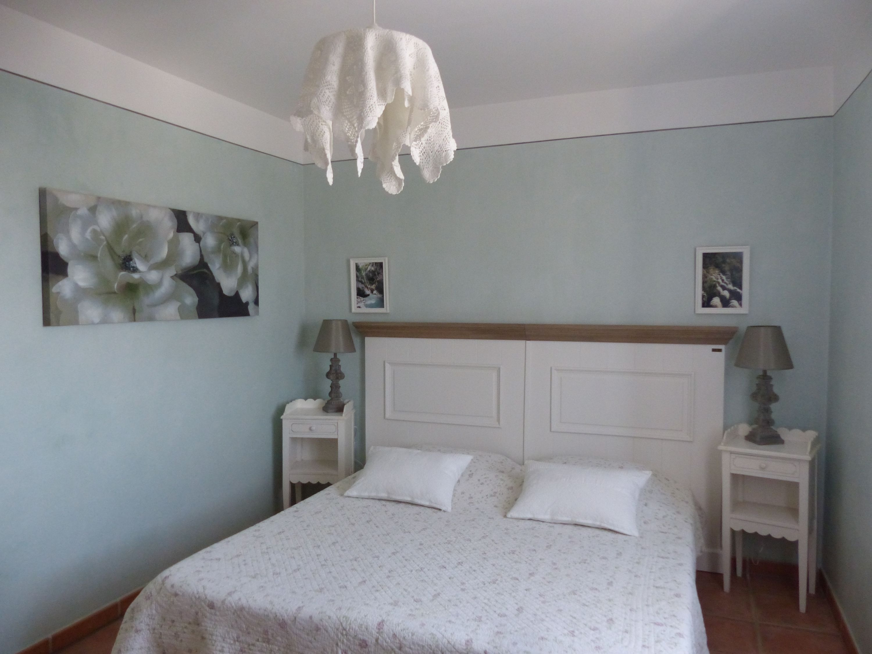 Una camera da letto con un letto, due comodini, una lampada a sospensione e due quadri appesi al muro.