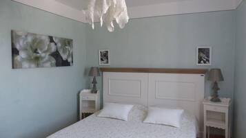 Una camera da letto con un letto, due comodini, una lampada a sospensione e due quadri appesi al muro.