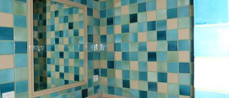 Un baño con un salpicadero de azulejos a cuadros, un espejo y un lavabo.