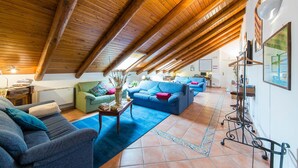 A spacious loft with high ceilings, exposed wooden beams, and a cozy living area with sofas and a coffee table. - Beata Solitudo B&B (Agerola)