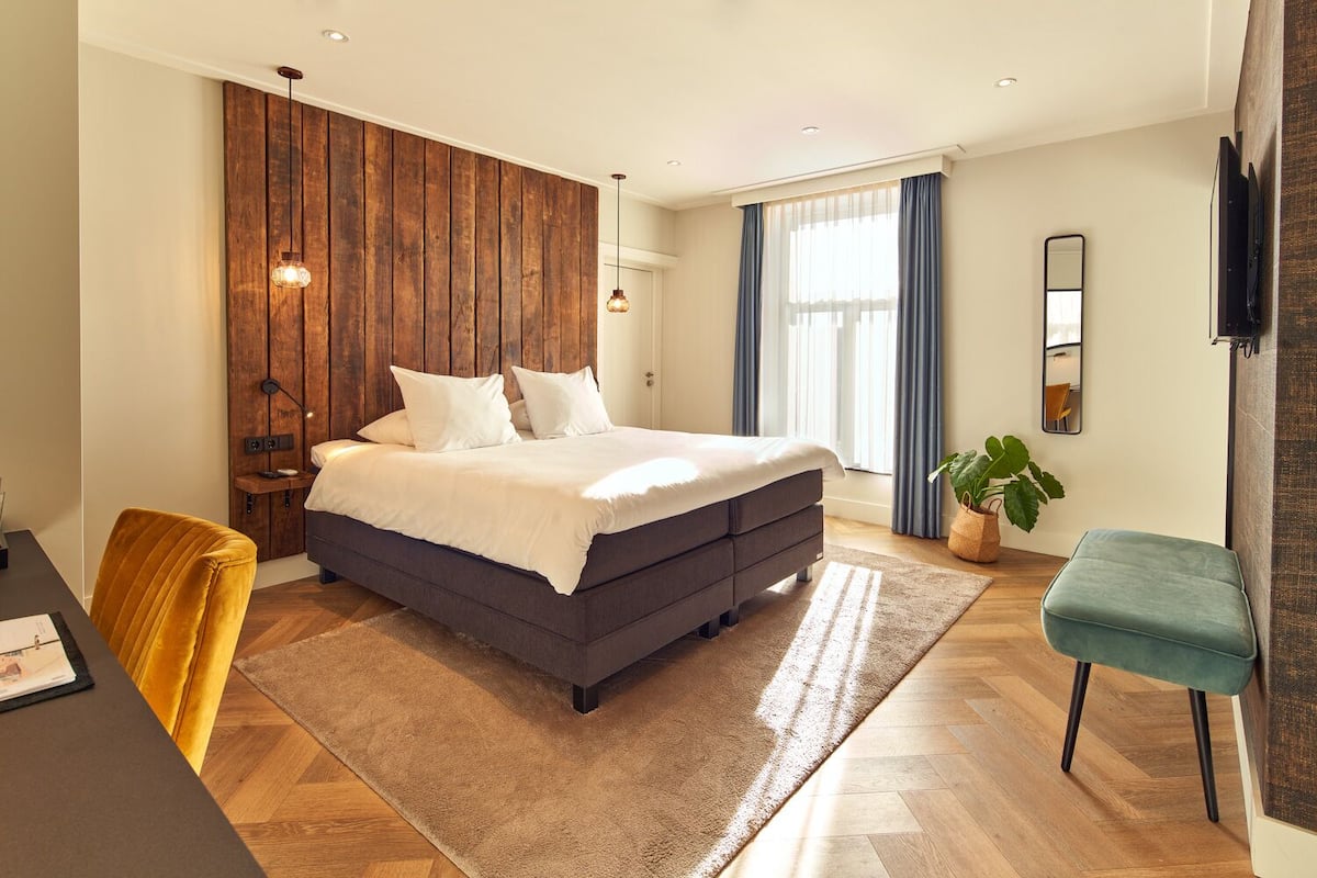 Un dormitorio moderno con una cama grande, un panel de madera en la pared y un escritorio con una silla.