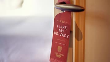 Porta de quarto de hotel com placa de privacidade e uma cama ao fundo.