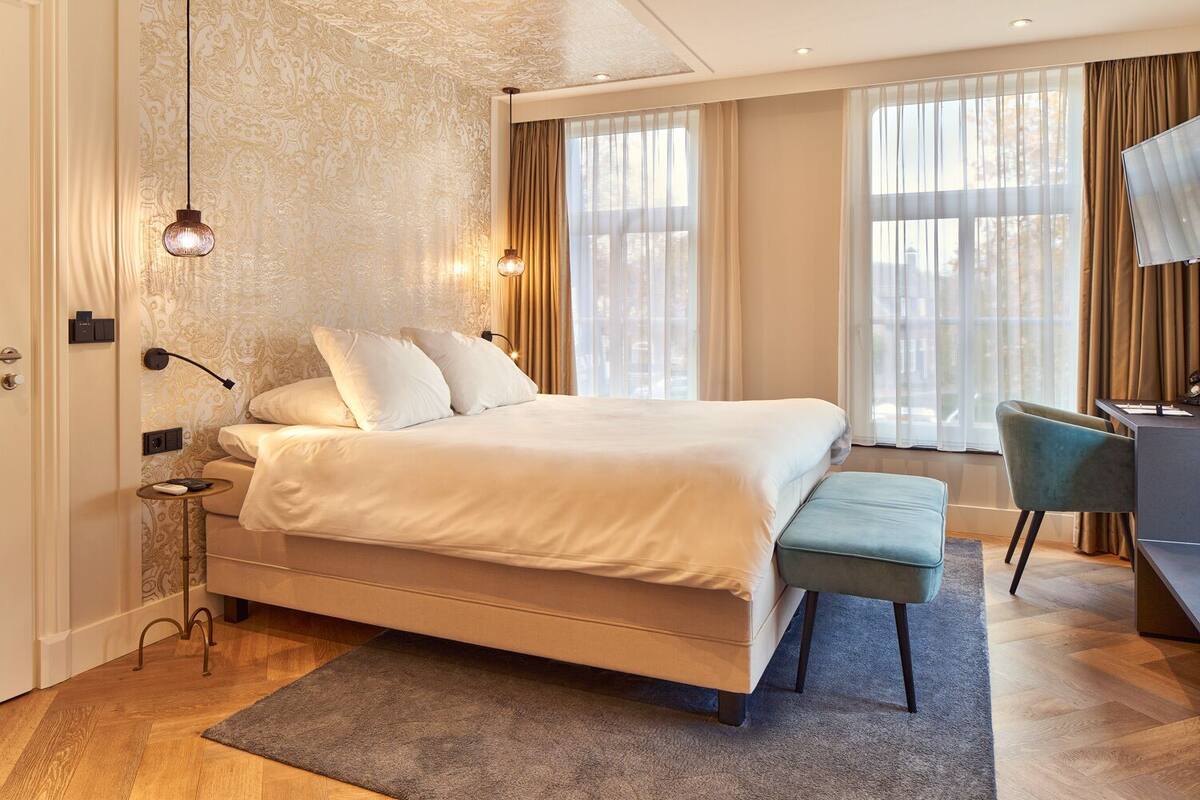 Una habitación de hotel moderna con una cama grande, un escritorio y una silla.