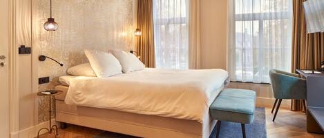 A modern hotel room with a large bed, a desk, and a chair.