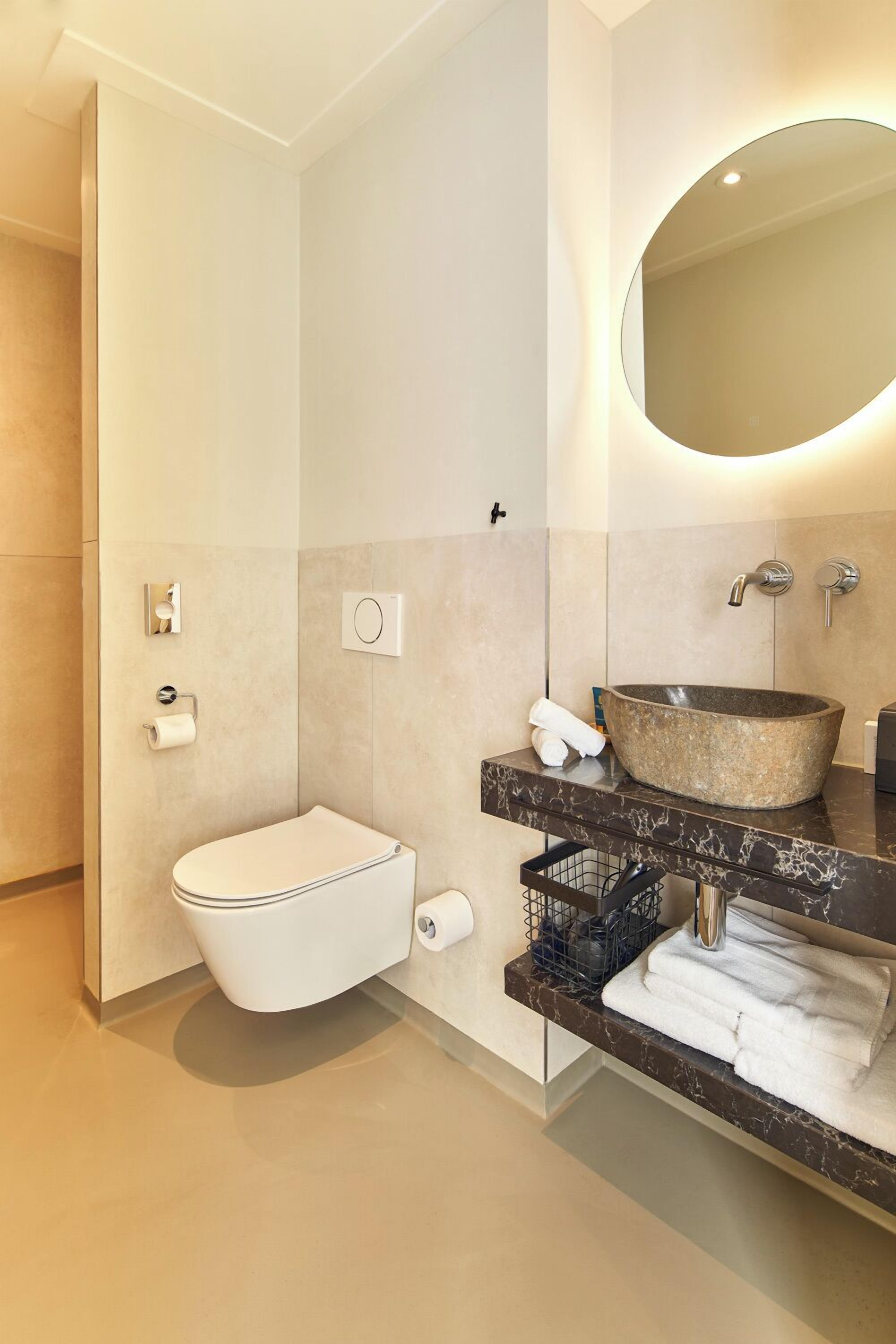 A modern bathroom with a toilet, sink, and large mirror.