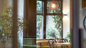 Un comedor moderno con separador de vidrio, mesa de madera, sillas metálicas e iluminación colgante.