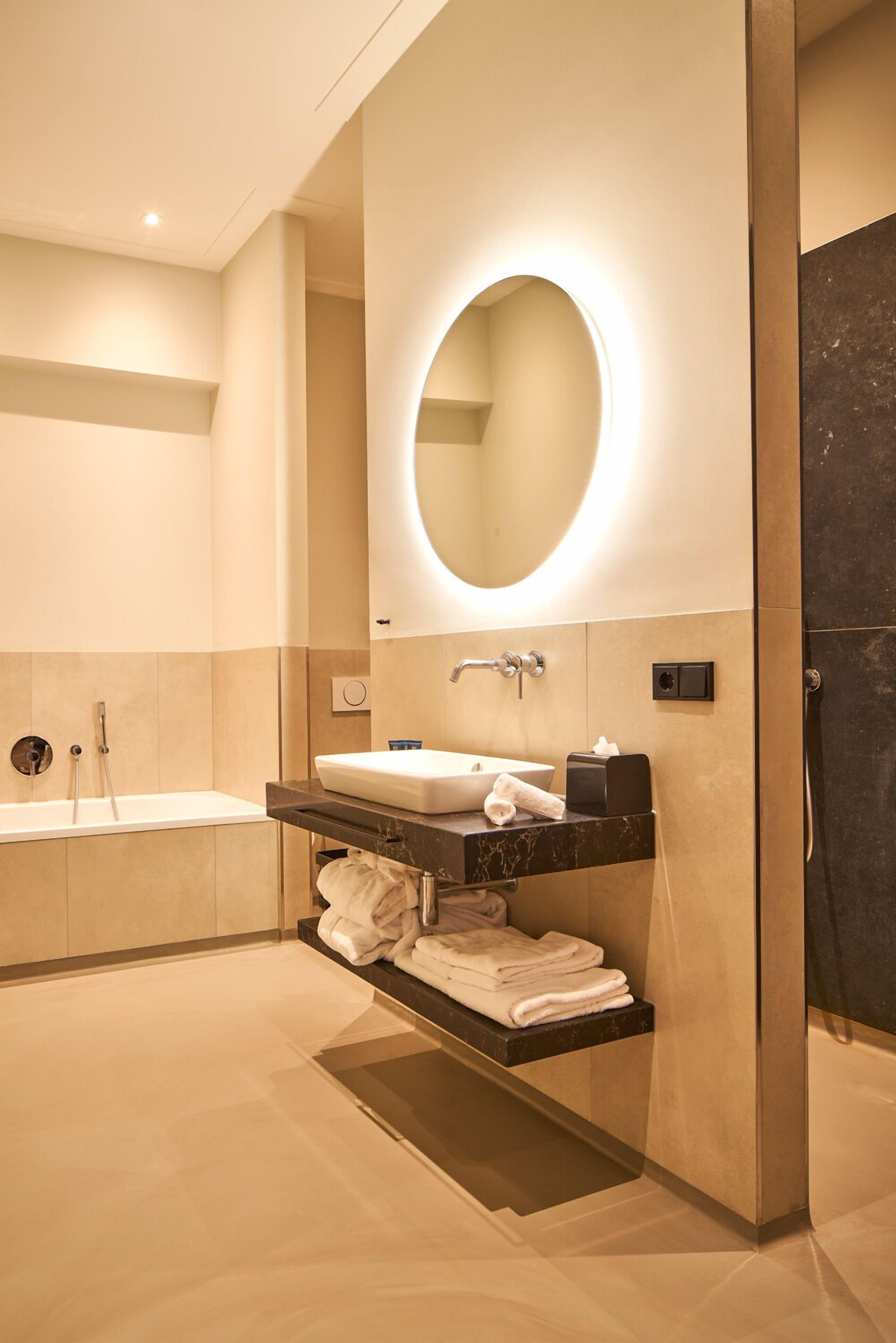 A modern bathroom with a bathtub, a sink with a mirror, and a towel rack.