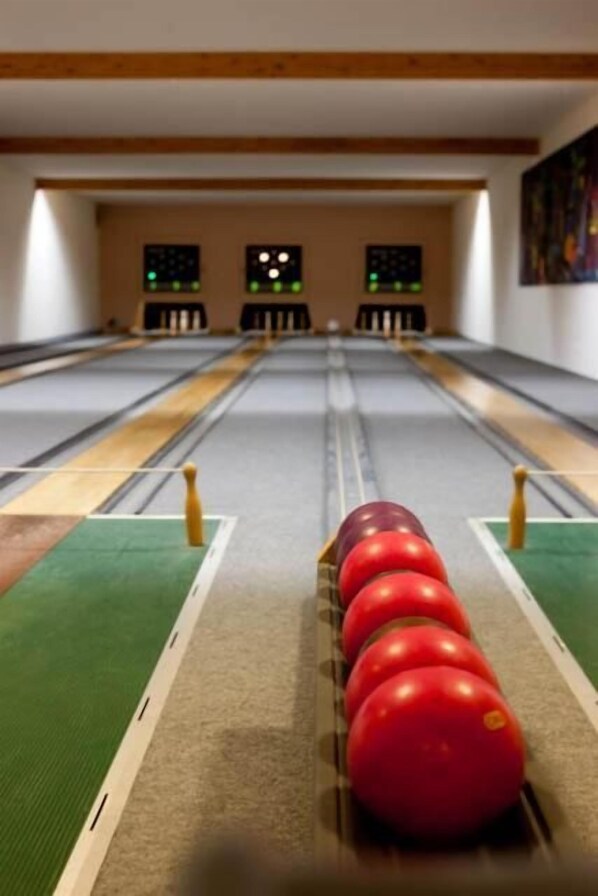 A bowling alley with multiple lanes, green carpeted areas, and bowling pins set up at the end of each lane. - Sporthotel Malchow (Malchow)