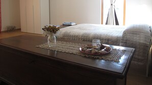 A neatly arranged bedroom with a bed, a bedside table with a vase and a glass, and a wooden dresser. - B&B Baratoff (Pesaro)