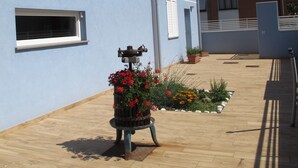 A courtyard with a blue building, a wooden bench with flowers, and a tiled floor. - B&B Baratoff (Pesaro)