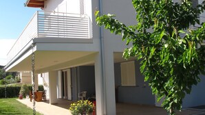 A two-story house with a covered patio, a small garden, and a tree. - B&B Baratoff (Pesaro)
