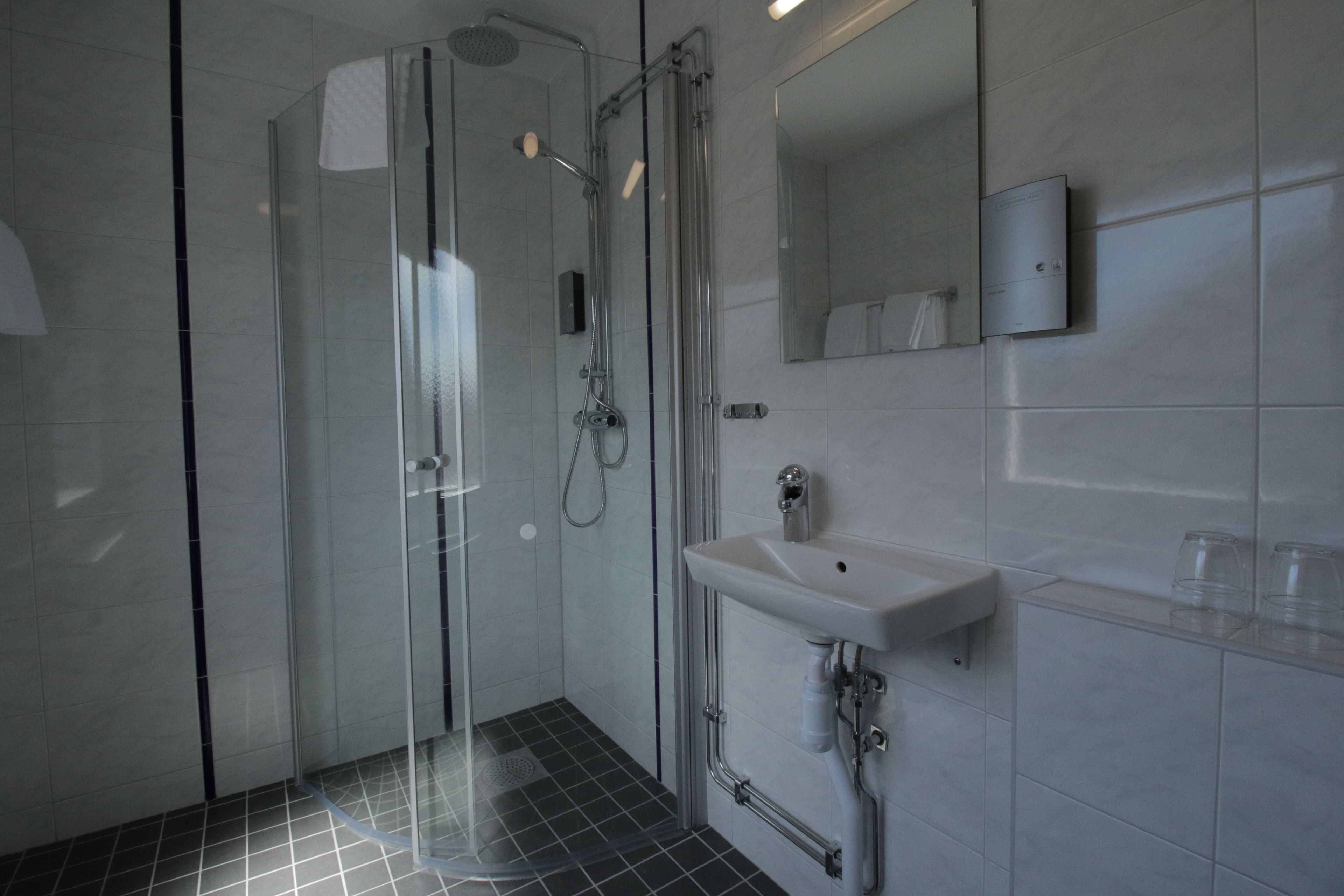 A modern bathroom with a glass-enclosed shower, a white sink, and a mirror above it.