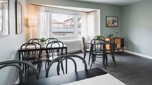 Un comedor con una mesa y sillas, un radiador, una ventana con cortinas y un armario con una planta.