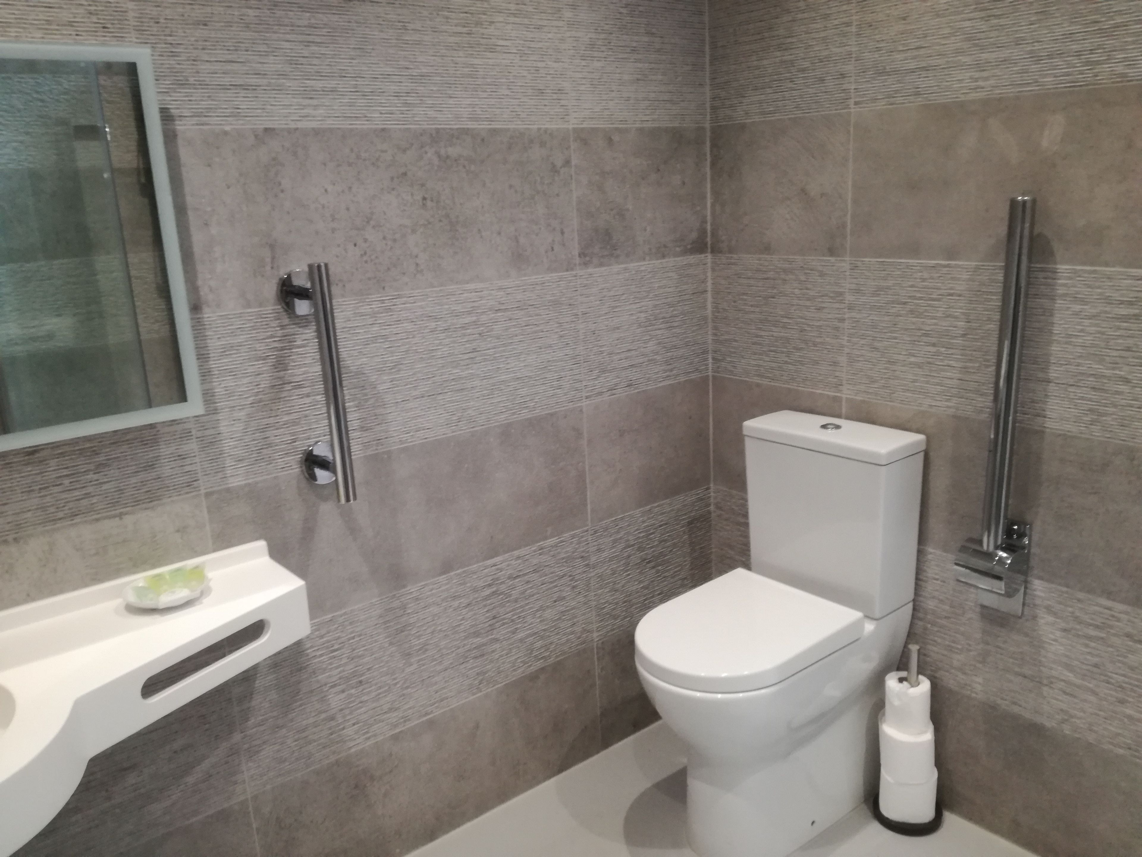 Un baño moderno con inodoro, lavamanos y espejo.