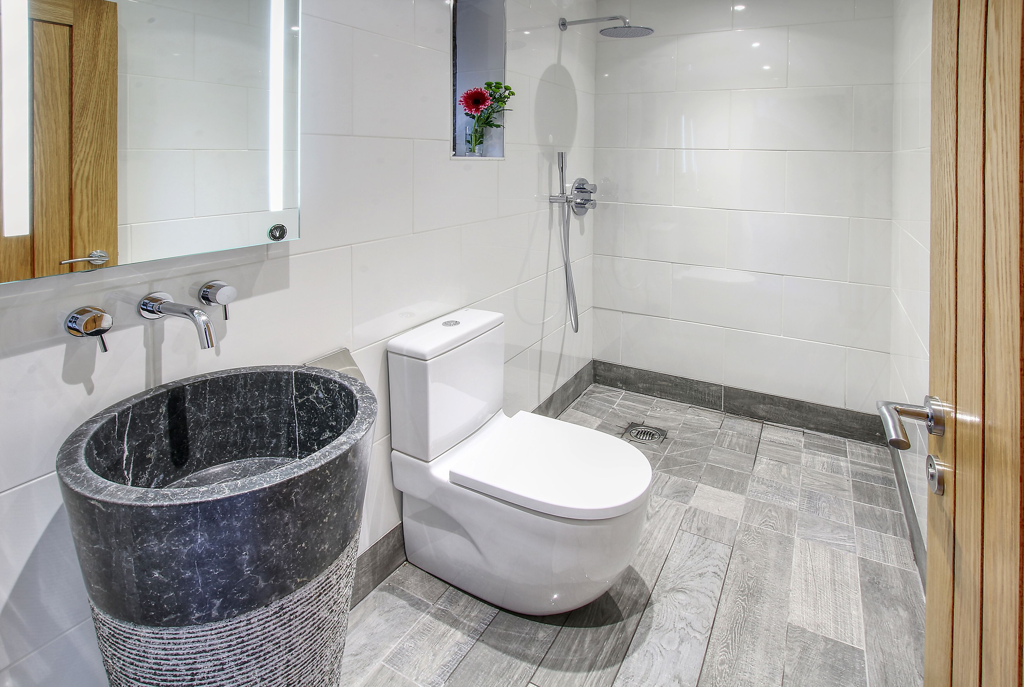 Ein Badezimmer mit Toilette, Bidet, Dusche und einem Marmorkorb.