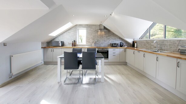 Een moderne keuken met een schuine kap, dakraam en een eethoek met een tafel en stoelen.