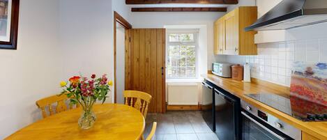 Una cocina con armarios de madera, estufa y una mesa de comedor con sillas.