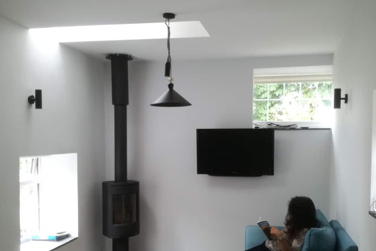 Een woonkamer met een open haard, een bank, een televisie en een persoon die leest.