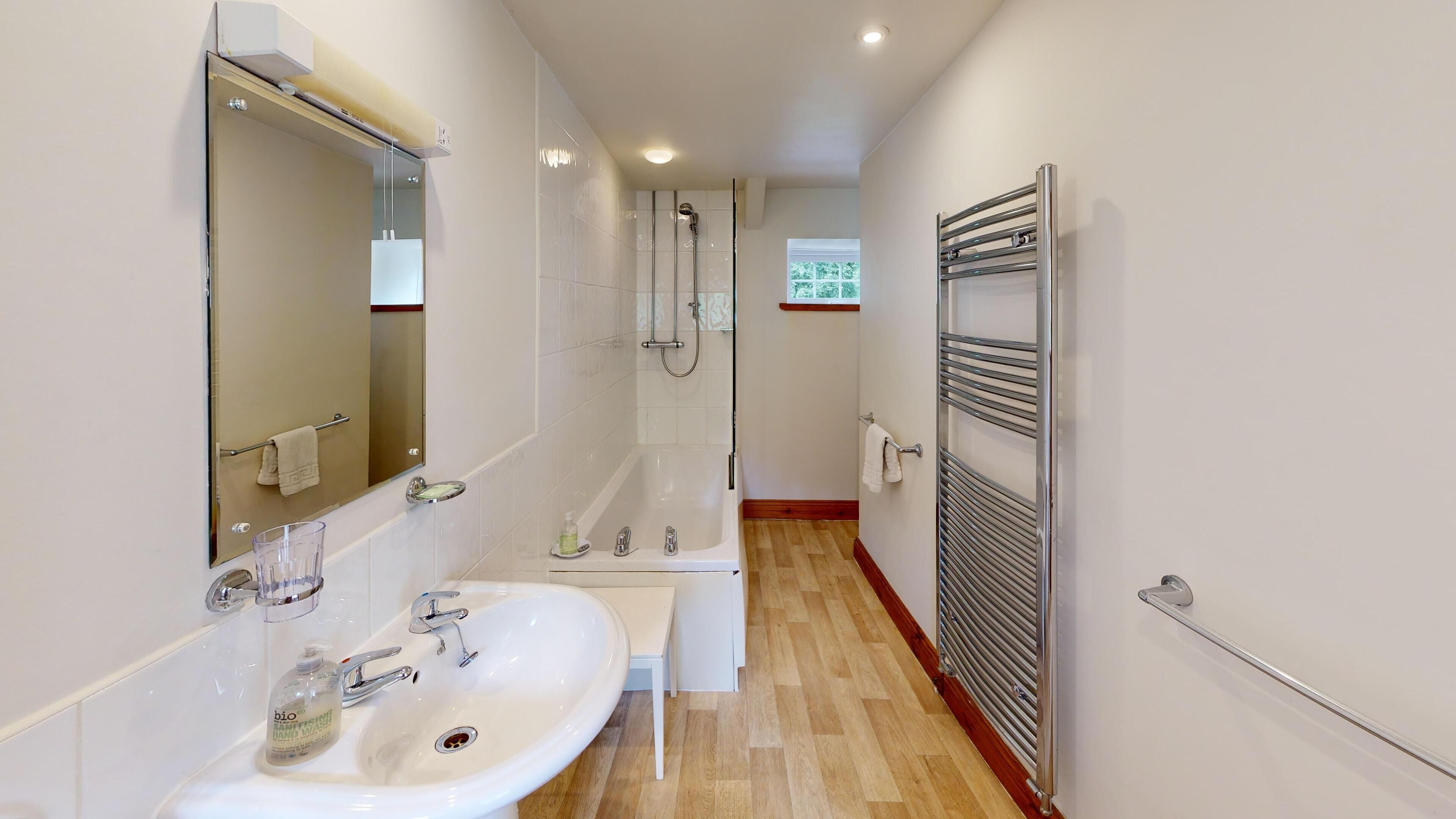 Une salle de bain moderne avec un grand miroir, un lavabo, une baignoire et une douche.