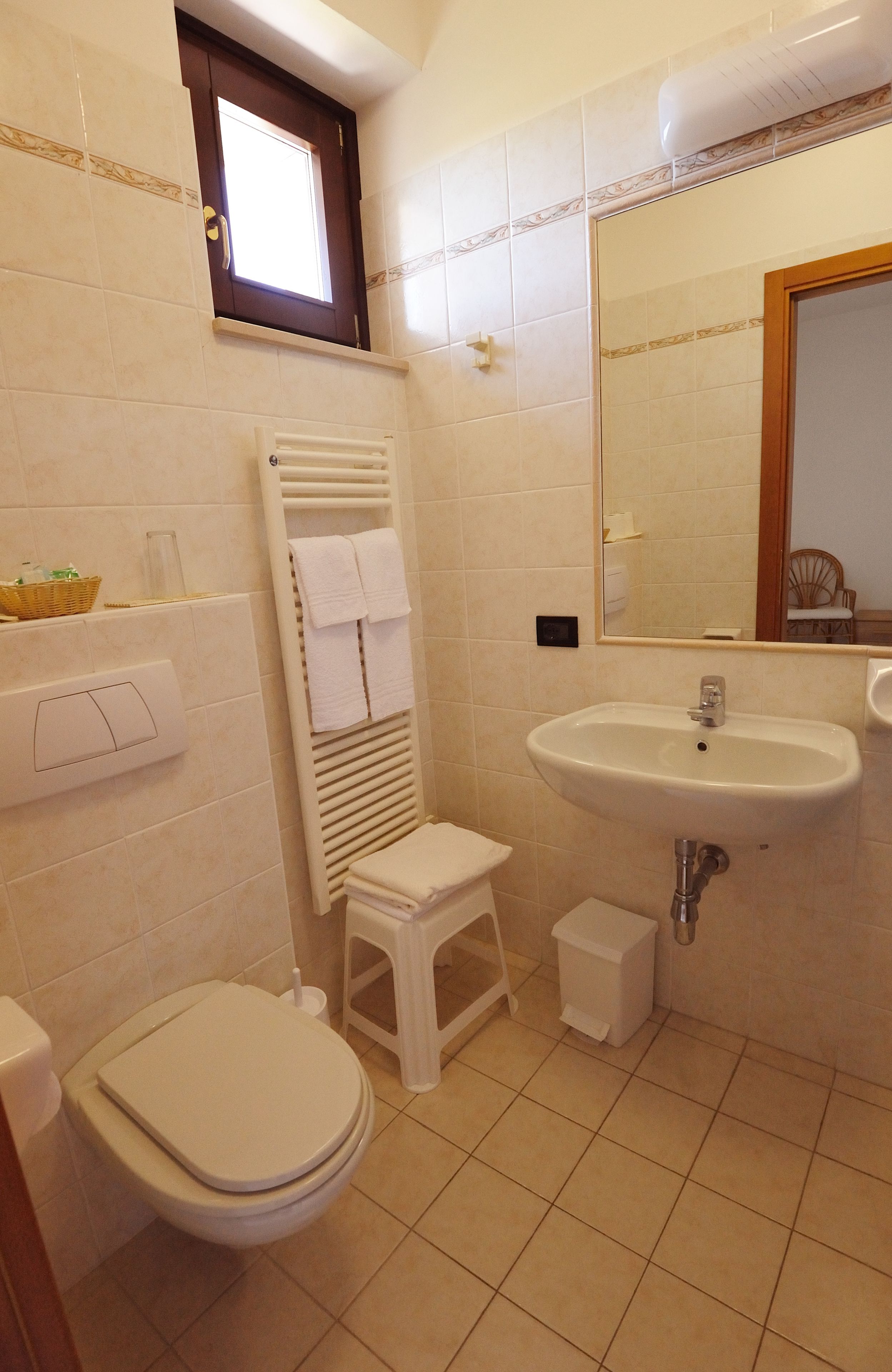 Une salle de bain équipée de toilettes, d’un lavabo, d’un miroir et d’un porte-serviettes.