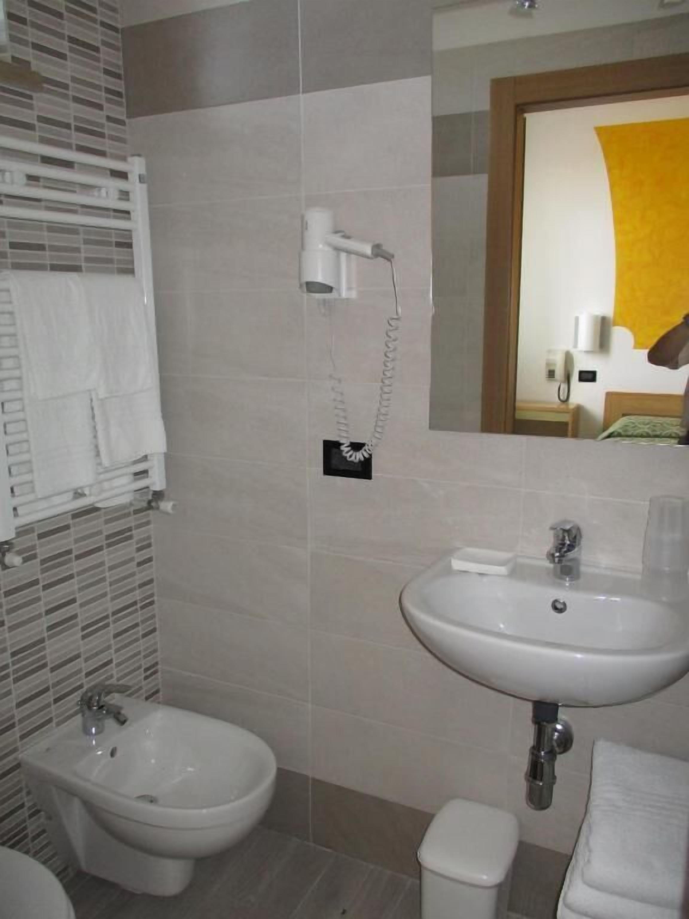 A bathroom with a bidet, a sink, and a mirror.