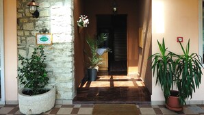 Techo de madera con tragaluces, pared de piedra, planta en maceta, una puerta y suelo de baldosas.
