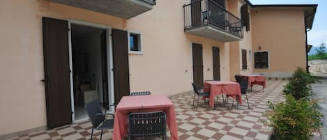 Un patio al aire libre con piso de cuadros, mesas con manteles rosas y sillas.