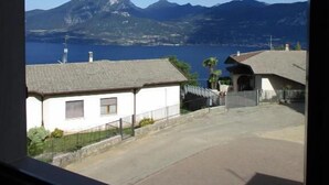 Vista de una zona costera con montañas al fondo, cielo despejado y un edificio de techo inclinado.