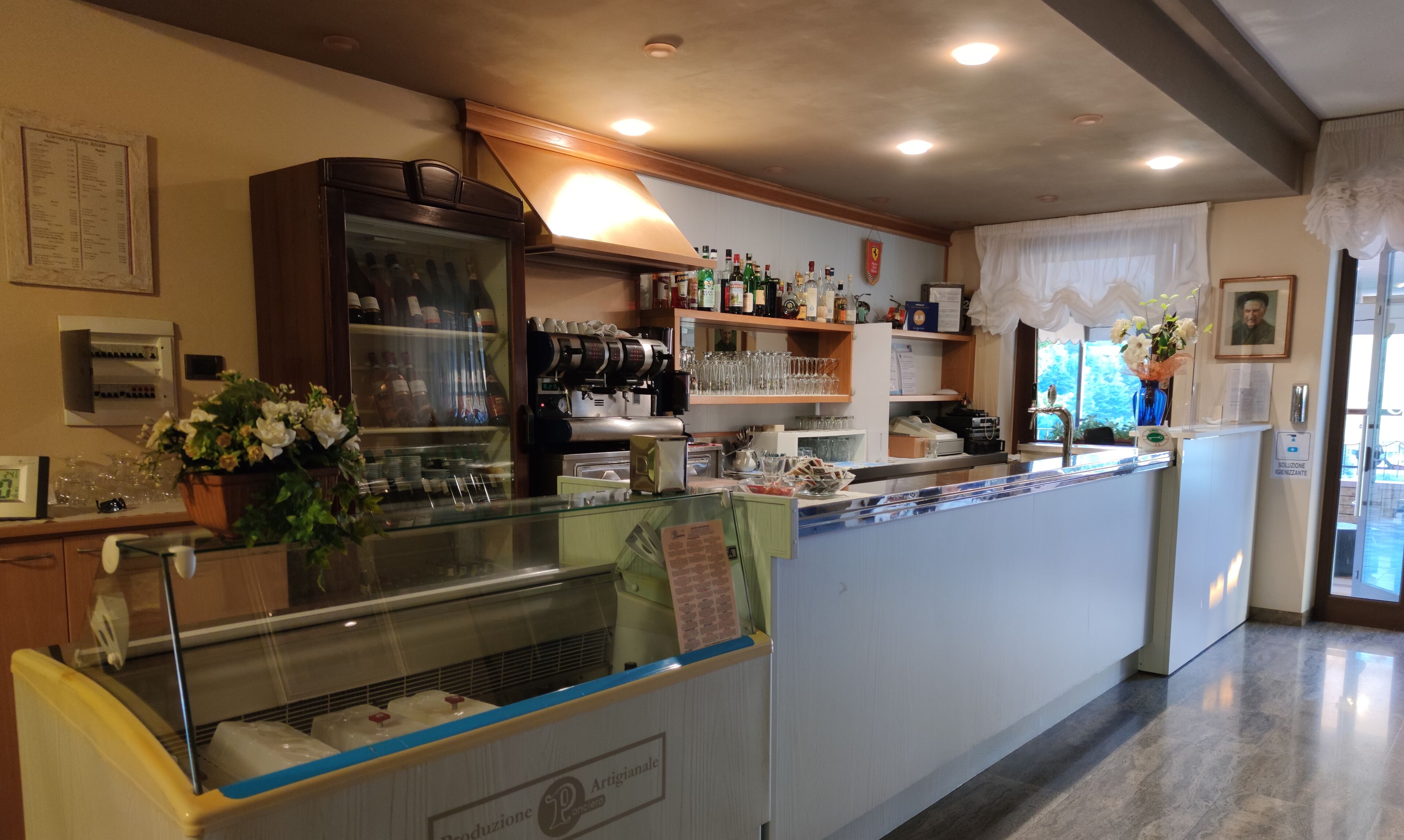 A cafe with a counter, shelves with bottles, a coffee machine, and a display case.
