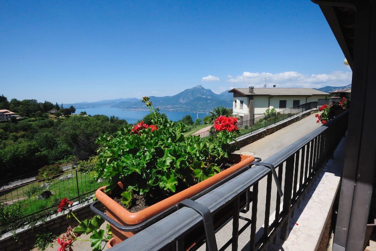 A balcony with a view of a mountainous landscape and a body of water.