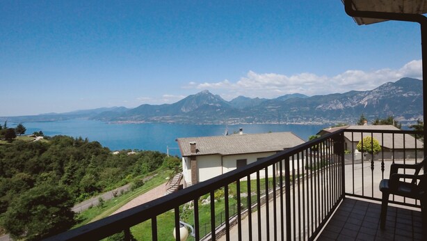 Un balcón con vista a un paisaje montañoso y una masa de agua.
