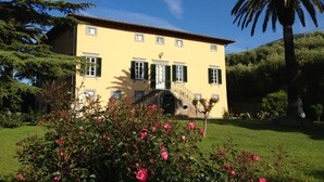 A two-story building with a yellow facade, green shutters, and a stone staircase leading to the entrance. - Fattoria di Fubbiano (Capannori)