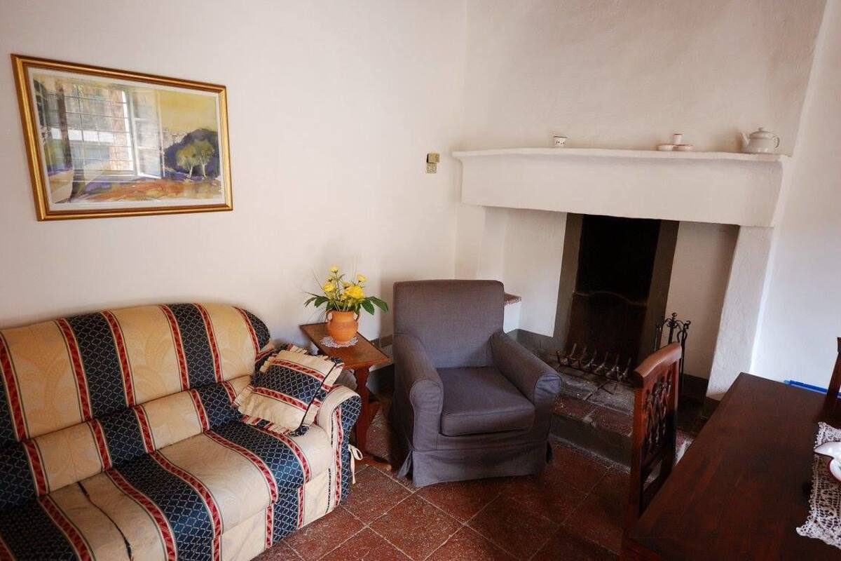 A living room with a sofa, armchair, fireplace, and a painting on the wall.