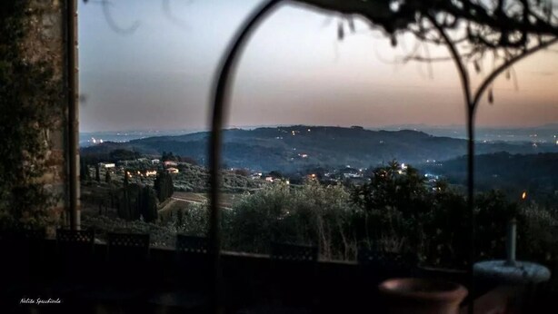 A view from a window overlooking a rural landscape at dusk with distant lights. - Fattoria di Fubbiano (Capannori)