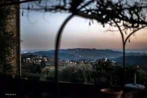 A view from a window overlooking a rural landscape at dusk with distant lights. - Fattoria di Fubbiano (Capannori)
