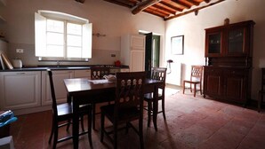 A kitchen with a dining table and chairs, a window, and a cabinet. - Fattoria di Fubbiano (Capannori)
