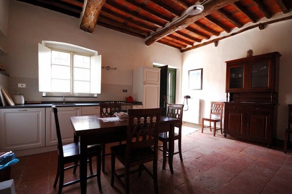 A kitchen with a dining table and chairs, a window, and a cabinet. - Fattoria di Fubbiano (Capannori)