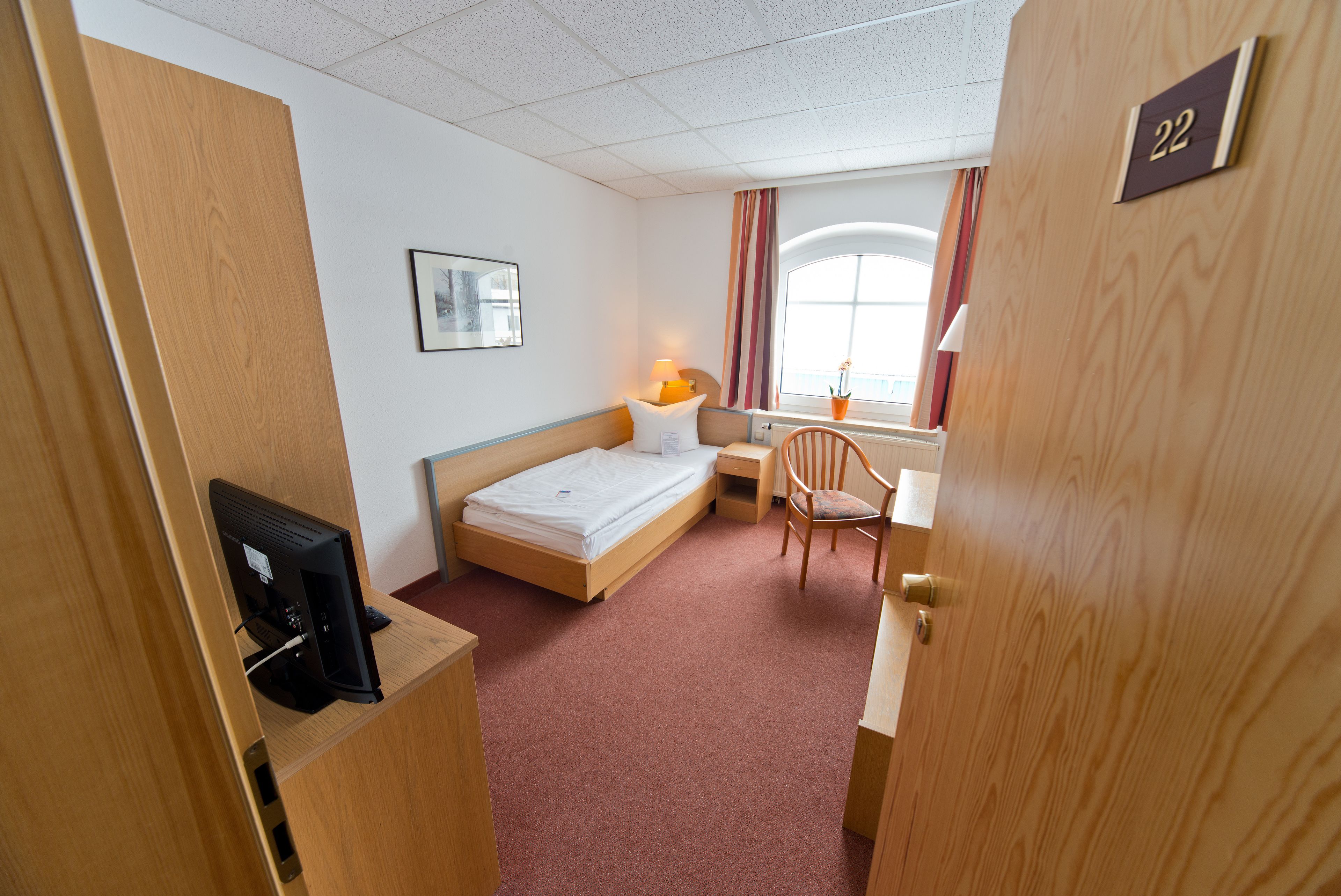 Een hotelkamer met een bed, bureau, stoel en een televisie.