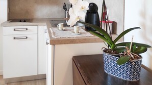 A modern kitchen with white cabinets, a wooden ceiling, and a potted orchid on the counter. - B&B Ai Musei (Brescia)
