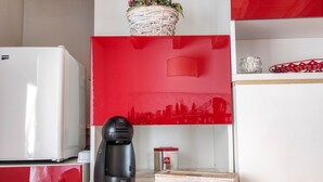 A kitchen with a red and white color scheme, a coffee maker, a basket with flowers, and a box labeled "TEA TIME". - B&B Ai Musei (Brescia)