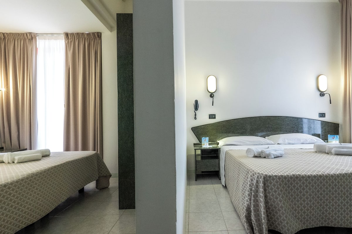 Una habitación de hotel con dos camas, una mesita de noche, un teléfono y un espejo.