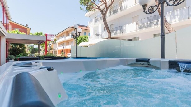 A hot tub in an outdoor setting with a view of residential buildings in the background. - Hotel Nobel (Rimini)