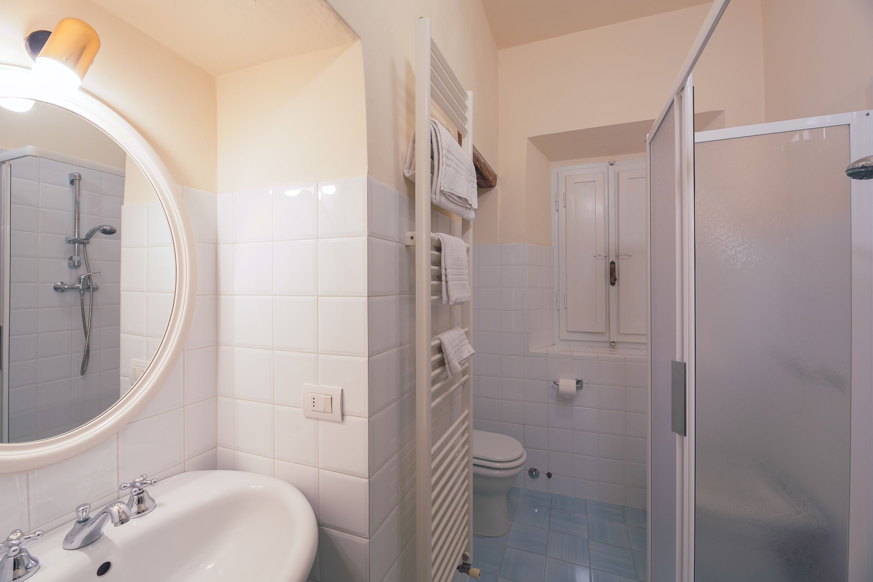 A bathroom with a white sink, a mirror, a shower, and a toilet.