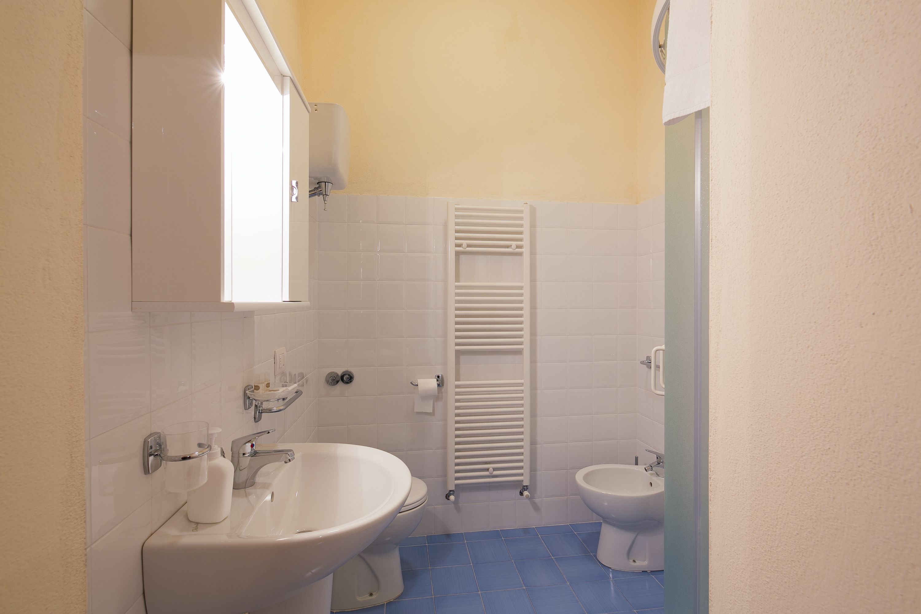Ein Badezimmer mit Waschbecken, Toilette, Bidet und Handtuchhalter.