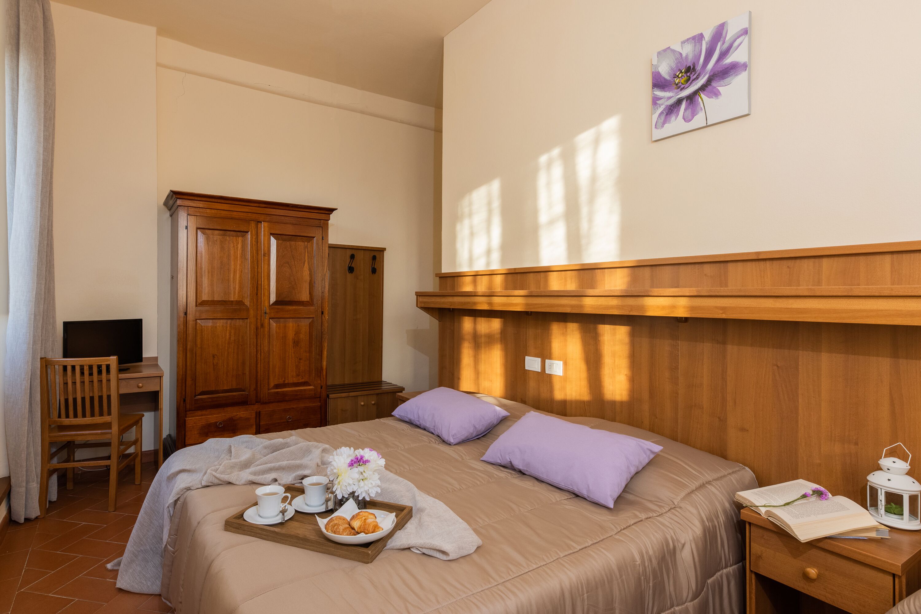 Un dormitorio con cama, armario de madera, escritorio, silla y un cuadro en la pared.