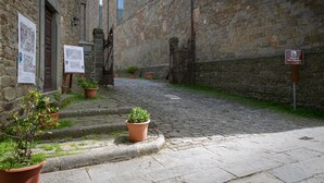 Una calle adoquinada con macetas de terracota y un cartel que indica la ubicación de la iglesia de San Francesco.