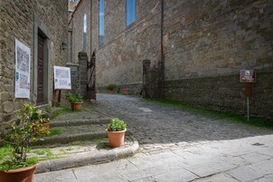 Egy kövezett utca, melynek mentén terrakotta színű virágtartók találhatók, és egy tábla jelzi a San Francesco-templom helyét.