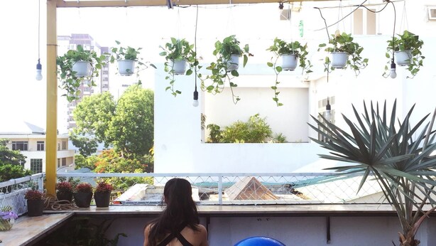 En balkon med træningsudstyr, plantekrukker og udsigt til bygninger.
