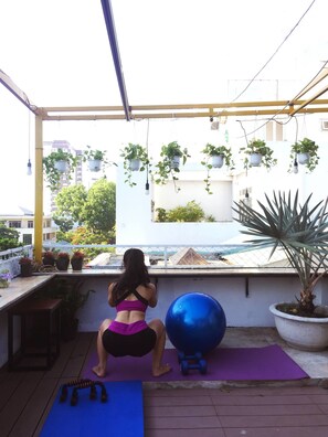 A balcony with exercise equipment, potted plants, and a view of buildings. - Nang Capsule Hostel (Da Nang)