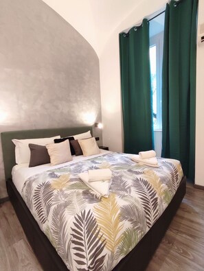 A bedroom with a large bed, green curtains, and a view of the outdoors. - Chroma Italy - Chroma Deka (Rome)